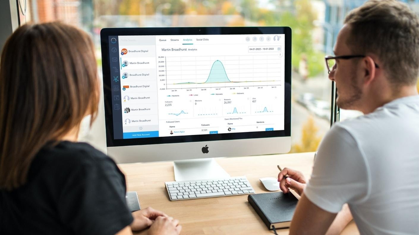 Two people looking at vbout social analytics dashboard